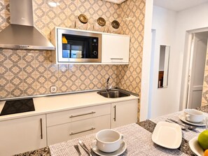 A modern kitchen with a microwave, stove, and sink. There are cabinets and a countertop with a patterned backsplash. - One bedroom, balcony, Wi-Fi, El Médano centre (El Médano)