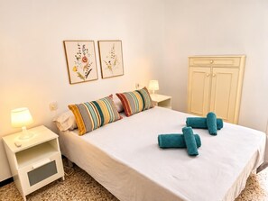 A hotel room with a bed, two bedside tables, a lamp, a wardrobe, and two framed botanical prints on the wall. - One bedroom, balcony, Wi-Fi, El Médano centre (El Médano)