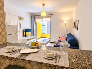 A modern kitchen with a dining area, a sofa, and a balcony with yellow walls. - One bedroom, balcony, Wi-Fi, El Médano centre (El Médano)