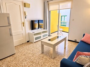 Ein modernes Wohnzimmer mit einem Flachbildfernseher, einem weißen Couchtisch und einem blauen Sofa.