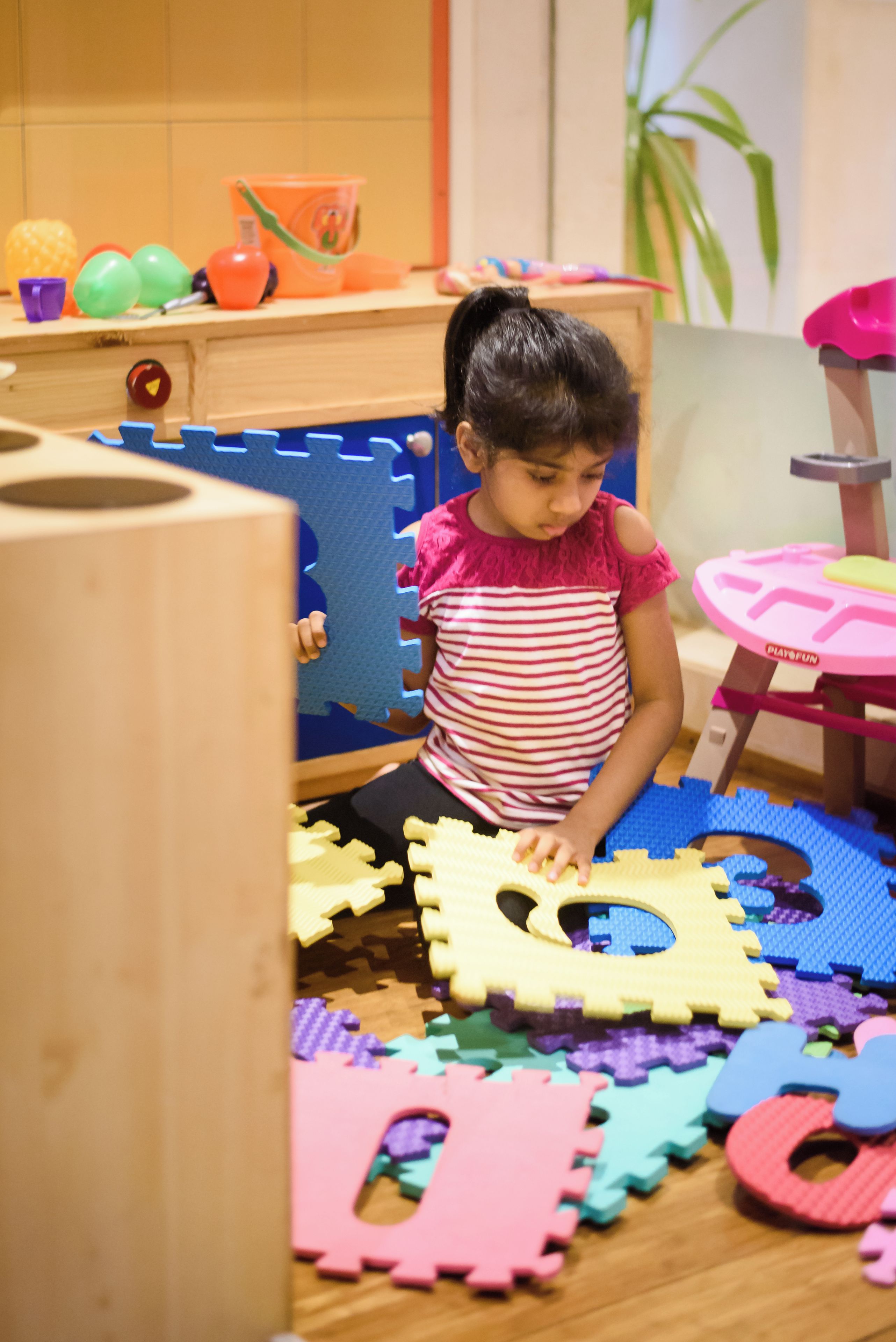 A child playing with puzzle pieces on a wooden play mat.