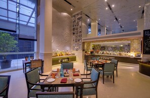 Un comedor moderno con mesas, sillas y una barra de buffet.