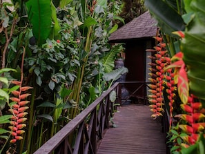 A wooden pathway leading to a building surrounded by lush tropical vegetation. - Novotel Goa Resort And Spa (Candolim)