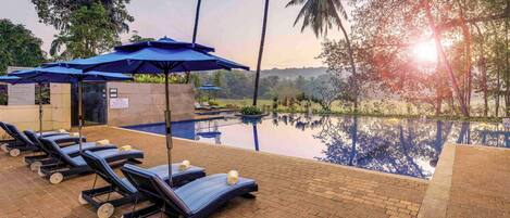A poolside area with lounge chairs, umbrellas, and a clear view of the surrounding landscape.