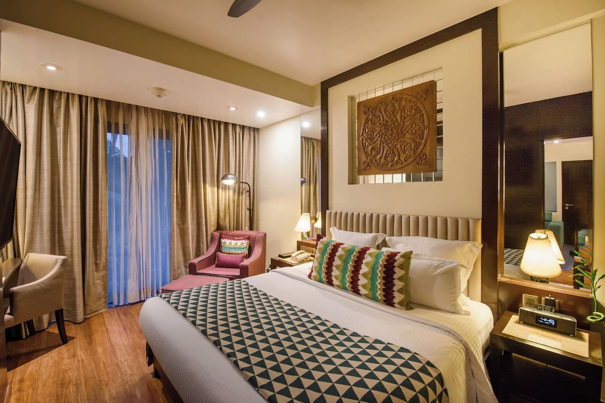 A hotel room with a bed, a desk, a chair, a TV, and a large mirror.