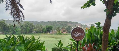 A sign for 'Vero Cibo' restaurant with a view of a green field and trees.