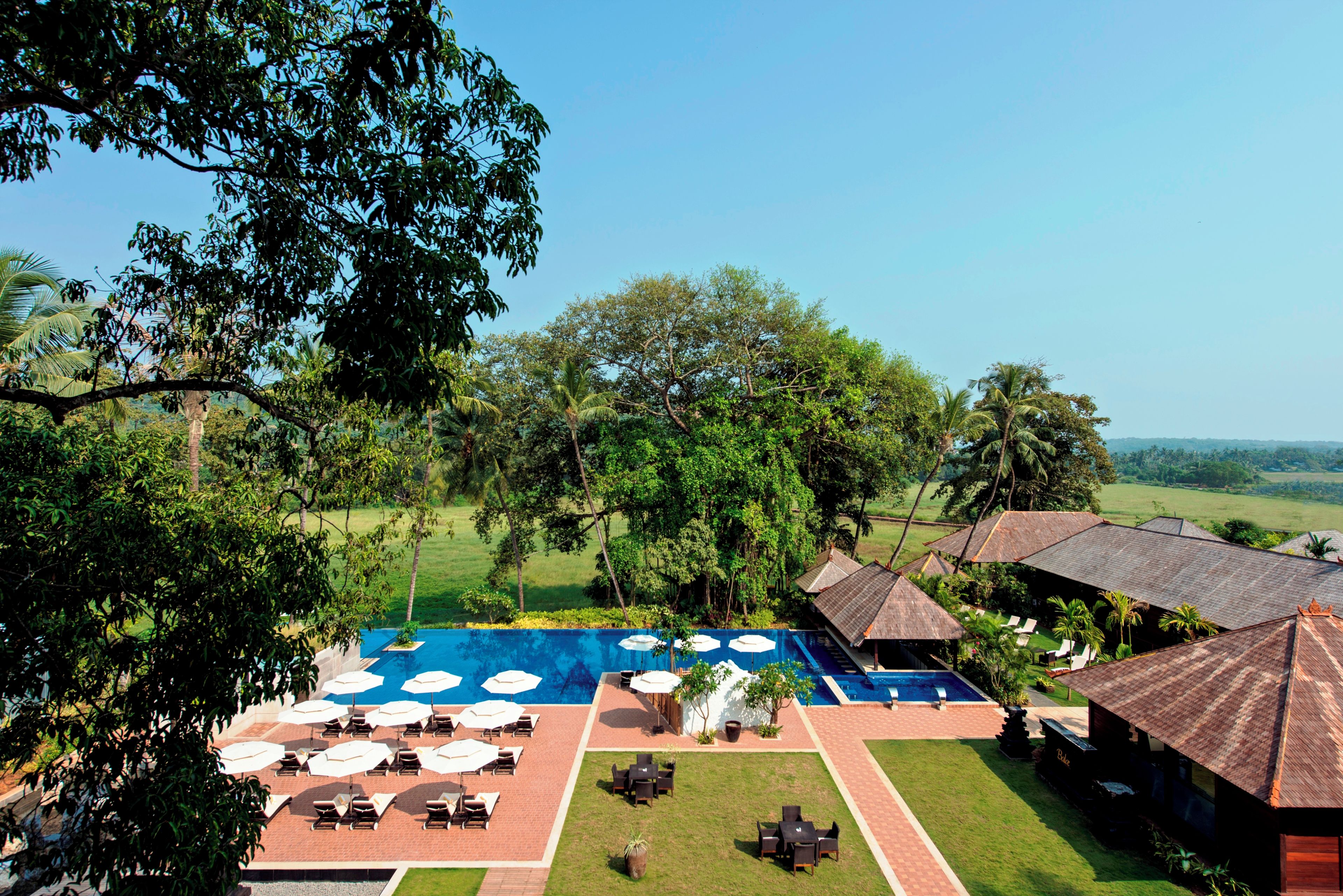 Ein Resort mit Pool, Terrassenmöbeln und üppiger Bepflanzung.
