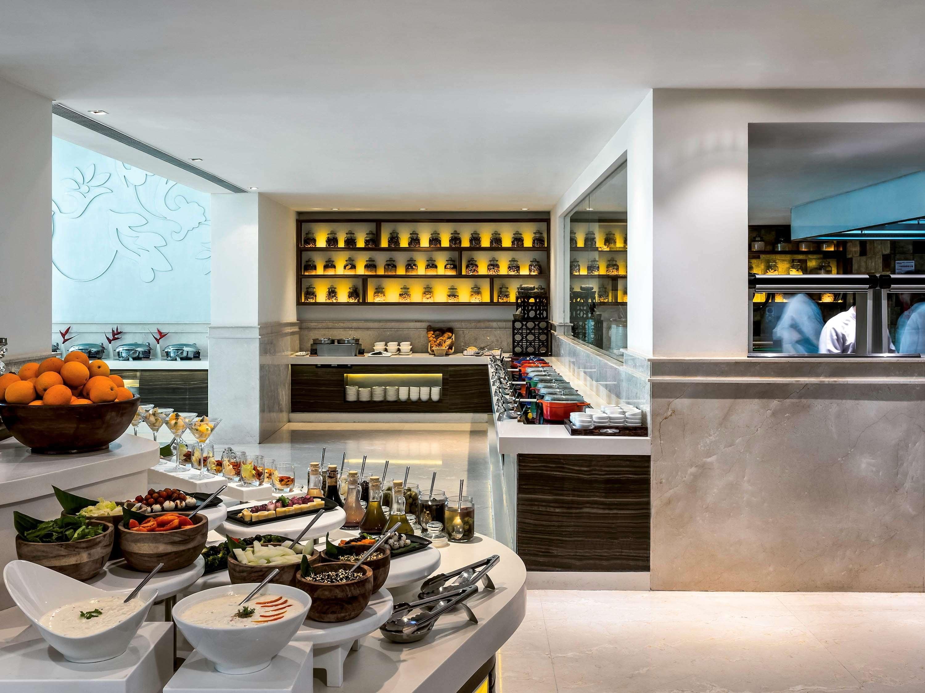 A buffet setup with various food items and beverages, a display of kitchenware, and a view of the kitchen area.