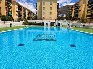 A swimming pool with a logo in the center, surrounded by multi-story buildings with balconies. - 3 bedrooms, swimming pool, parking, 100 metres from the sea, Wi-Fi (Los Cristianos)