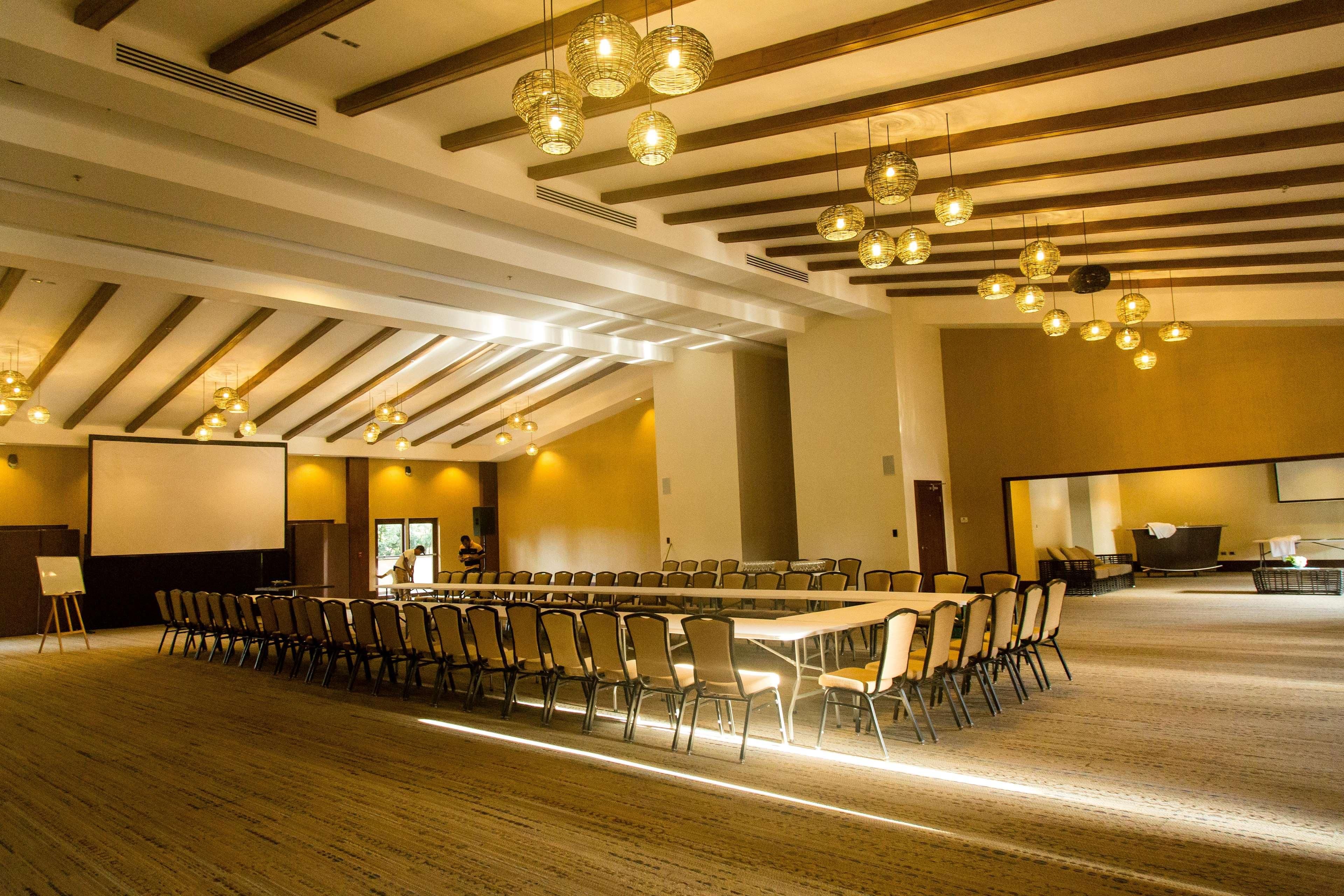 A conference room with a long table, chairs, and hanging lights.