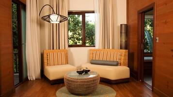 A room with two sofas, a round woven coffee table, a hanging light fixture, and a window with curtains.