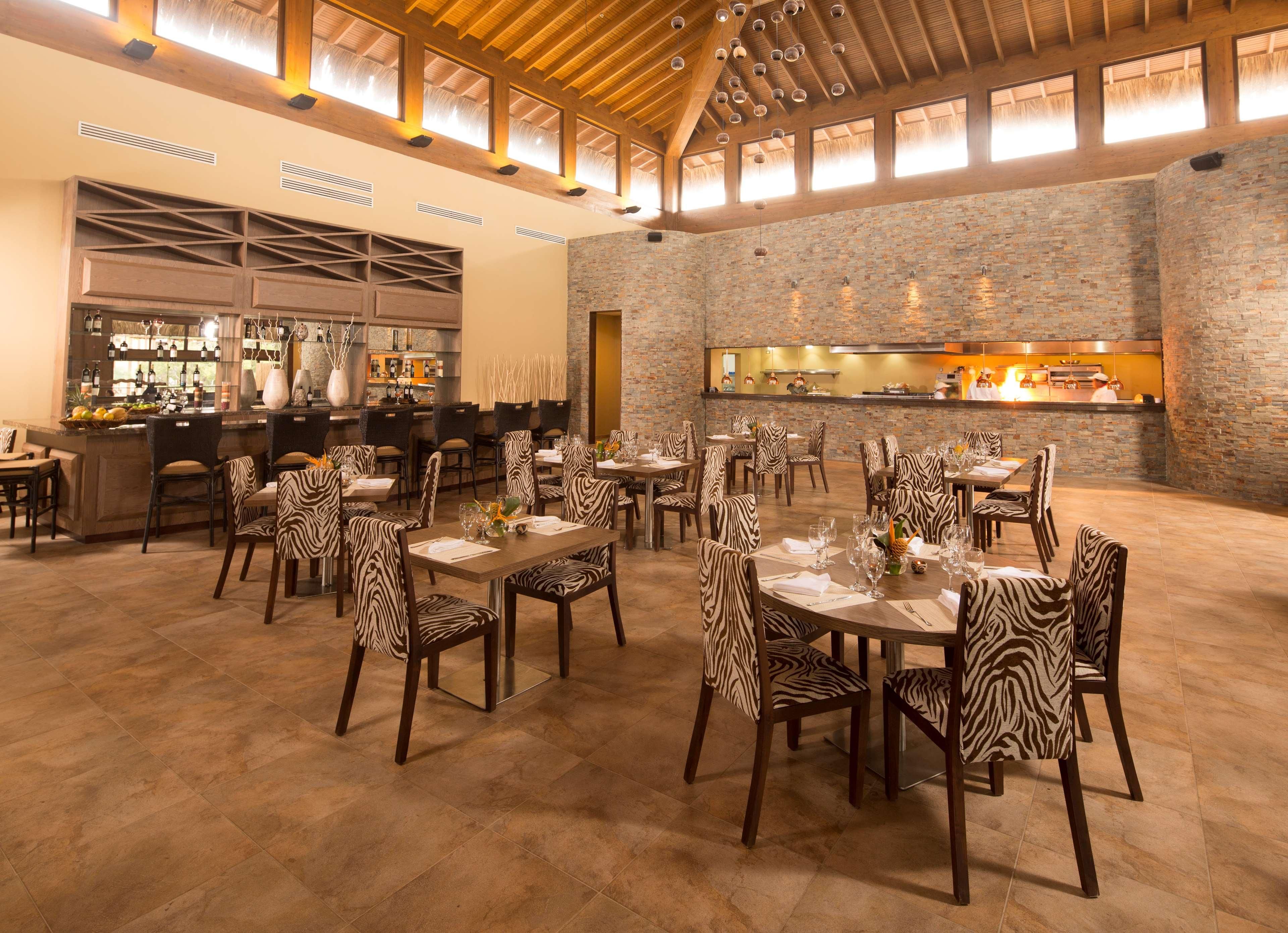 A restaurant with zebra-striped chairs, a bar area, and a stone wall.