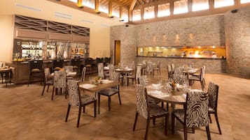 A restaurant with zebra-striped chairs, a bar area, and a stone wall.