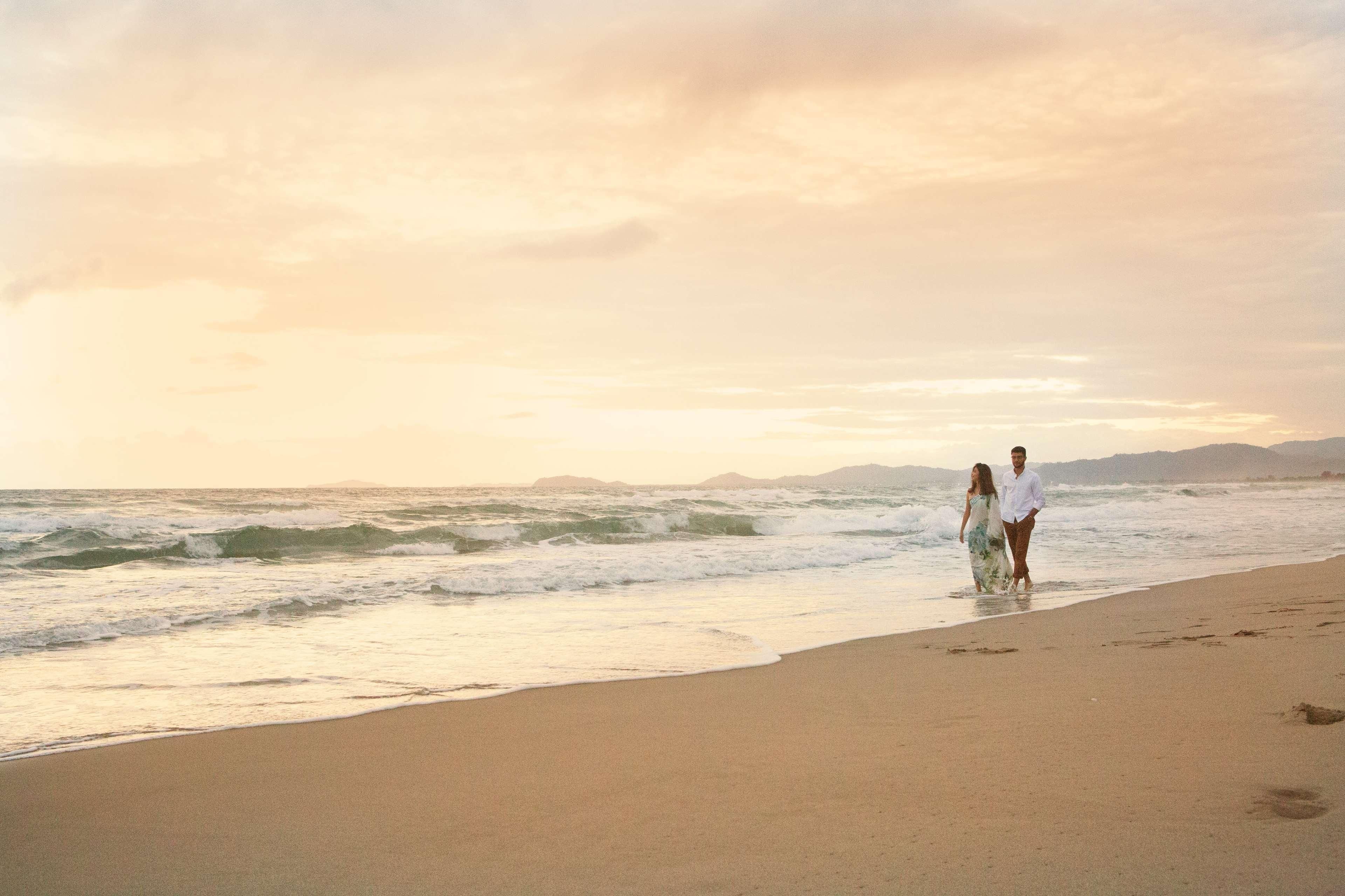 Une plage où l’on voit un couple se promener le long du rivage.