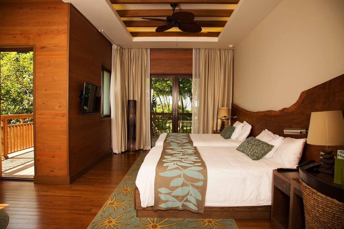 Un dormitorio espacioso con una cama grande, un ventilador de techo y vistas a zonas verdes.