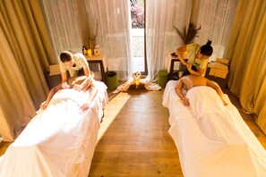 Una habitación con dos camas, una mesita y una ventana con cortinas.