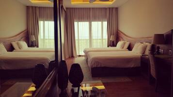 A hotel room with two beds, a large mirror, ceiling fans, and a desk with a lamp.
