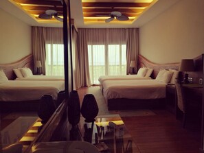 A hotel room with two beds, a large mirror, ceiling fans, and a desk with a lamp. - Indura Beach & Golf Resort, Curio Collection (Tela)