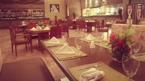 A restaurant with tables set for dining, a bar area, and a stone wall.
