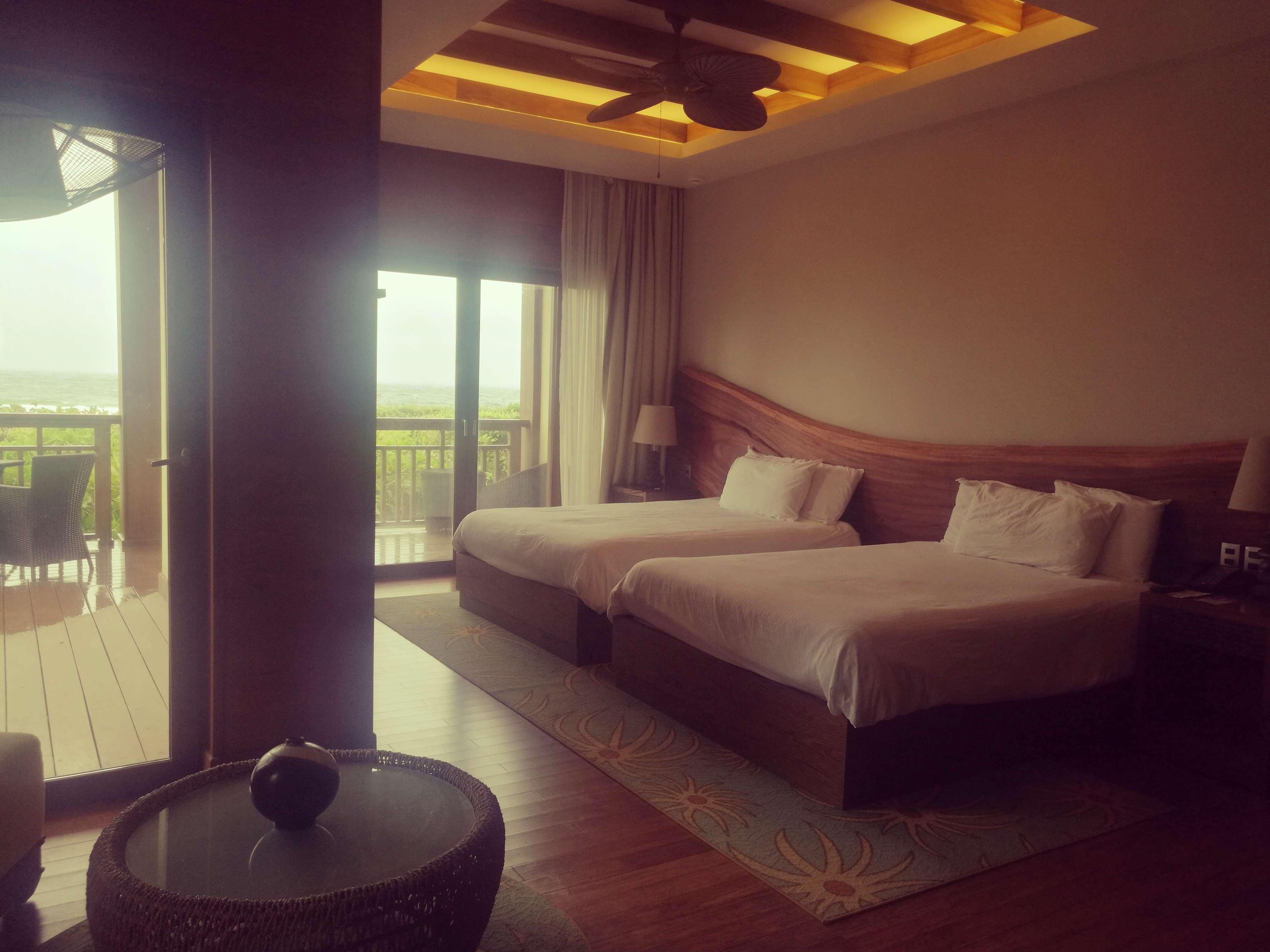 A hotel room with two beds, a balcony, and a round table.