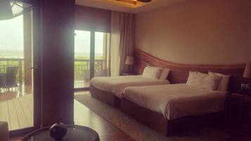 A hotel room with two beds, a balcony, and a round table.
