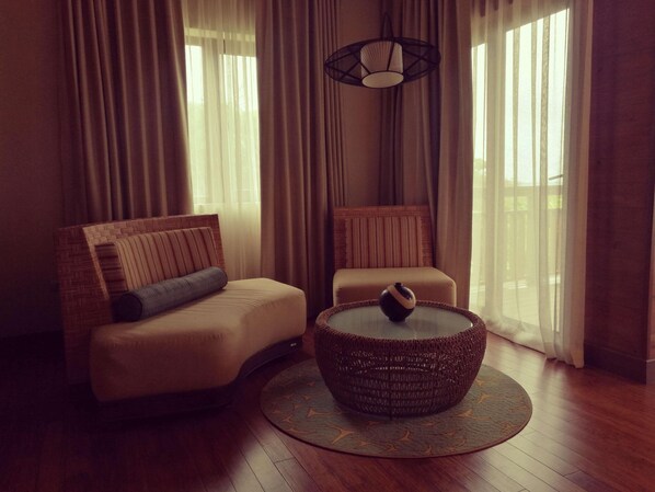 A modern living room with a sofa, a smaller chair, a round coffee table, and a hanging light fixture. - Indura Beach & Golf Resort, Curio Collection (Tela)