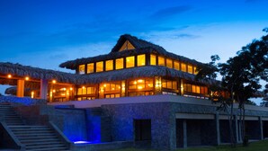 A two-story building with a thatched roof, large windows, and a stone base.