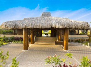 A thatched-roof structure with a staircase leading to a pool area.