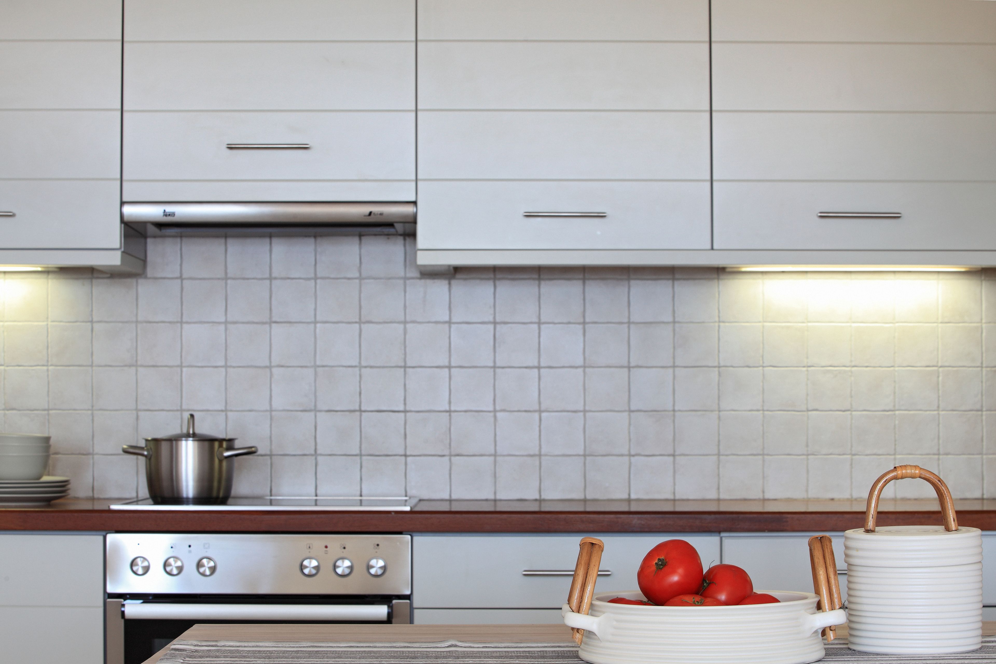 A kitchen with white cabinets, a stove, and a tiled backsplash.