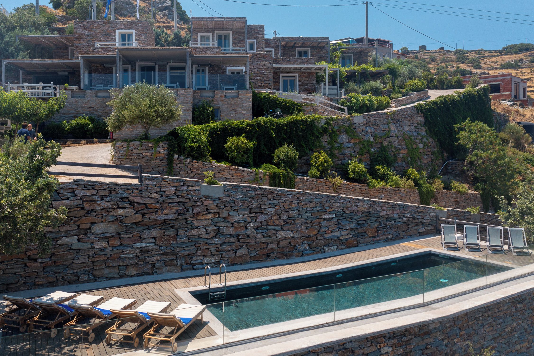 A stone-walled pool area with lounge chairs and a clear view of the surrounding hillside buildings.