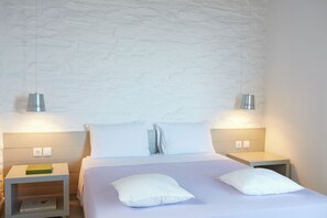 Une chambre d’hôtel bien aménagée, avec un lit, deux tables de chevet et un mur orné d’un motif texturé.
