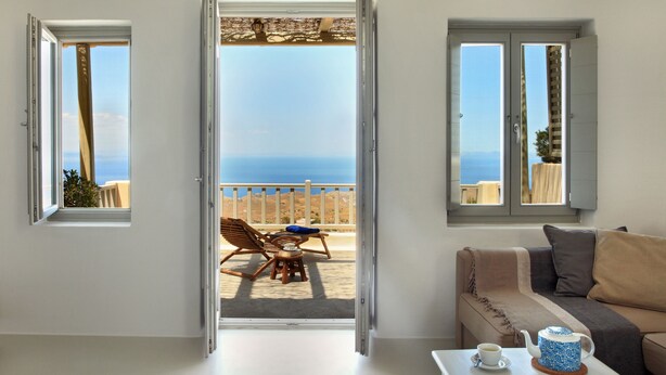 Una habitación con balcón, sofá, mesa de centro y vista al mar.