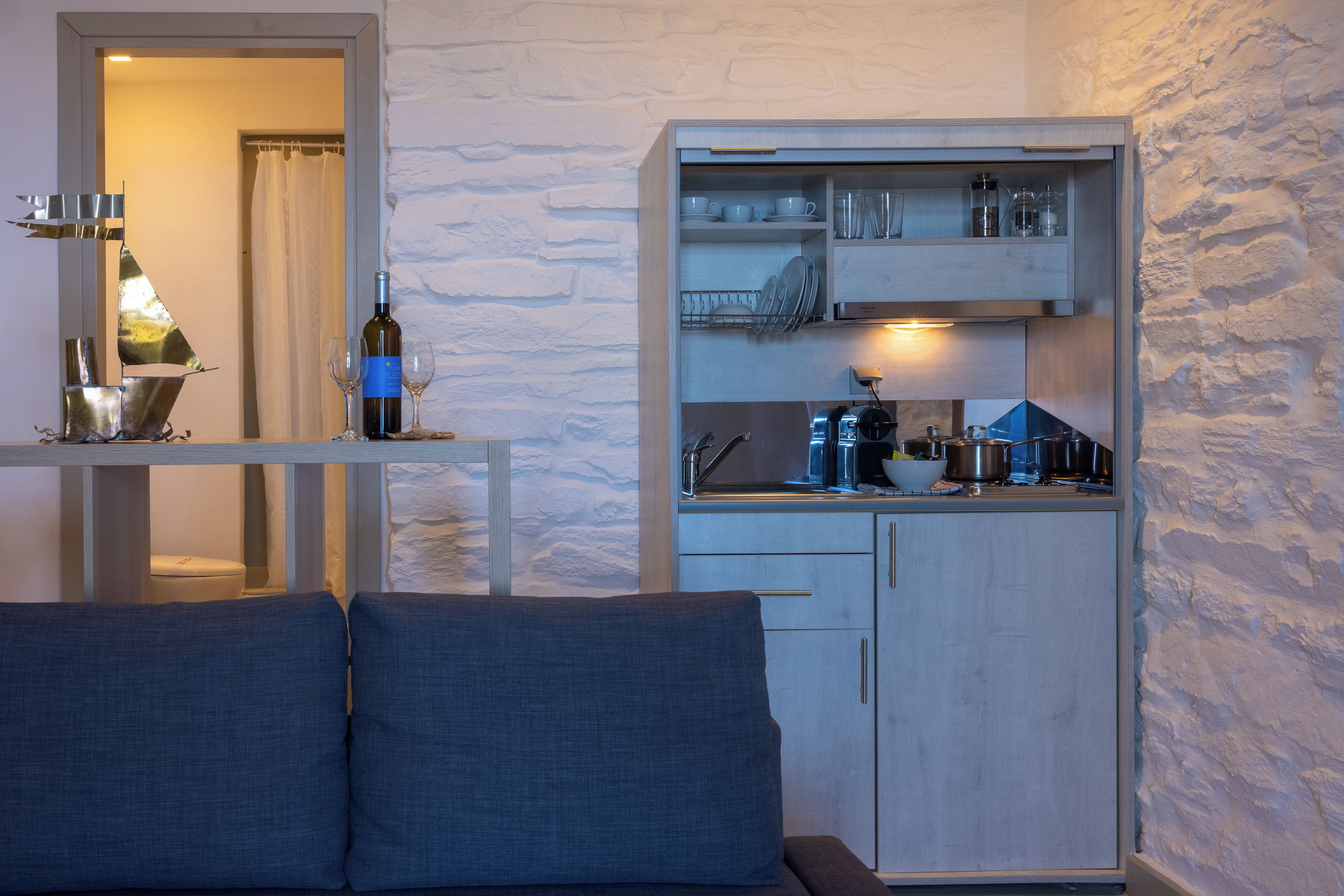 A compact living space with a kitchenette, a sofa with cushions, and a dining area with a table and chairs.