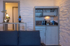 Un espacio habitable compacto con kitchenette, un sofá con cojines y un comedor con mesa y sillas.