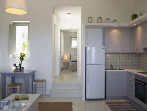 Una cocina moderna con refrigerador, horno y comedor con mesa y sillas.