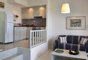 Une cuisine moderne avec des meubles blancs, un four encastré et un coin repas comprenant un canapé à rayures et une table basse.
