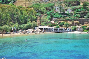 Un hôtel situé sur la côte, avec une plage, une eau cristalline et une végétation luxuriante.