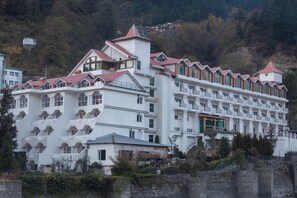 A large hotel with multiple floors, balconies, and a mountainous backdrop. - Citrus Manali Resorts (Manali)