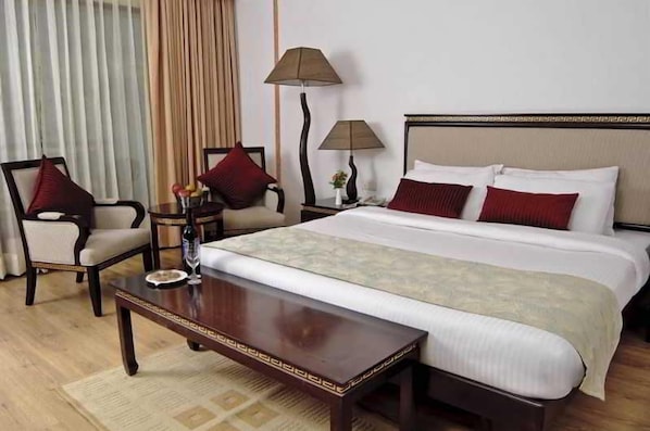 A hotel room with a bed, two bedside tables, a chair, a desk, and a lamp. - Citrus Manali Resorts (Manali)