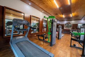 A gym with a treadmill, weight machines, and mirrors. - Citrus Manali Resorts (Manali)