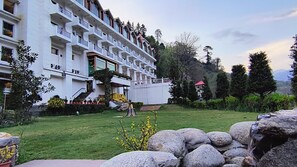 A multi-story hotel with balconies, a well-maintained lawn, and a mountainous backdrop. - Citrus Manali Resorts (Manali)
