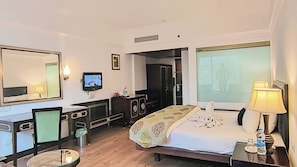 A hotel room with a bed, a desk, a television, a mirror, and a window. - Citrus Manali Resorts (Manali)