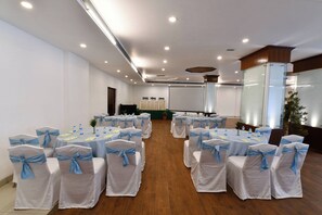 A conference room with rows of tables and chairs, white tablecloths, and blue chair sashes. - Citrus Manali Resorts (Manali)
