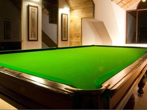 A pool table in a room with wooden walls and framed pictures. - Citrus Manali Resorts (Manali)