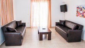 A living room with two leather sofas, a coffee table, and a flat-screen TV mounted on the wall. - Gennadi Garden Apartments (Rhodes)