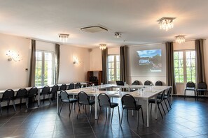A conference room with a long table, chairs, a projector screen, and a large window. - Hotel La Sapiniere (Hallines)