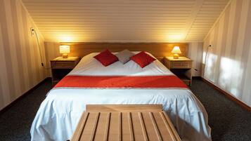 Een hotelkamer met een bed, twee nachtkastjes met lampen, een houten bankje en een vloerbedekking.