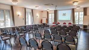 Een vergaderzaal met rijen stoelen, een scherm voor een beamer en een whiteboard.