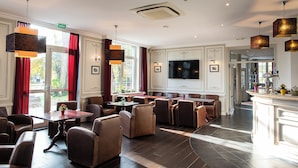 A hotel lobby with seating areas, a television, and a reception desk. - Hotel La Sapiniere (Hallines)