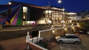 A modern building with a colorful facade and a parking area with a car. - The Devonshire Park Hotel (Eastbourne)